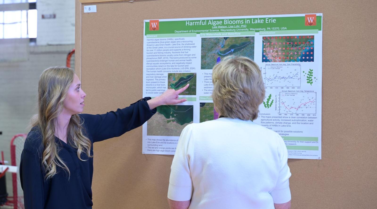 Waynesburg student shows poster presentation to faculty member