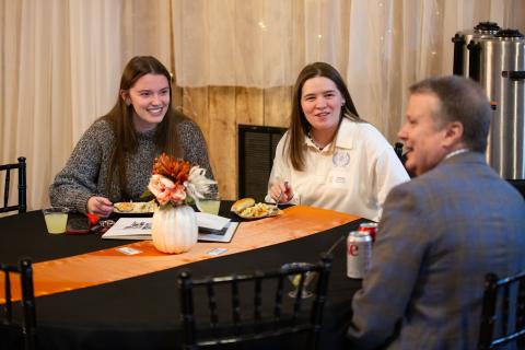 Two recent graduates speaking to President Lee during Homecoming 2024
