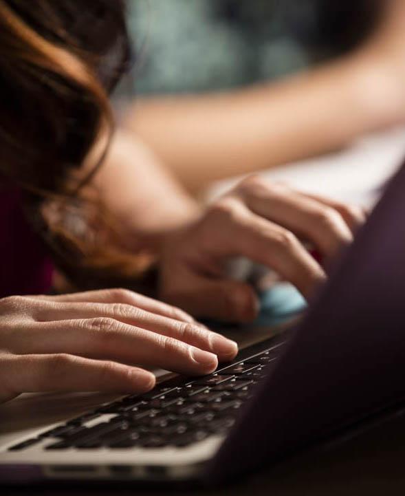 A student takes careful notes on thier laptop