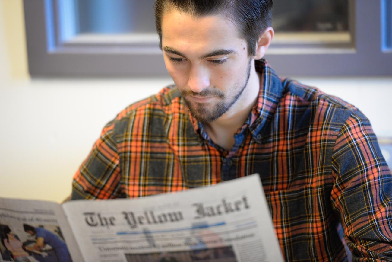 Student reads the university news paper.