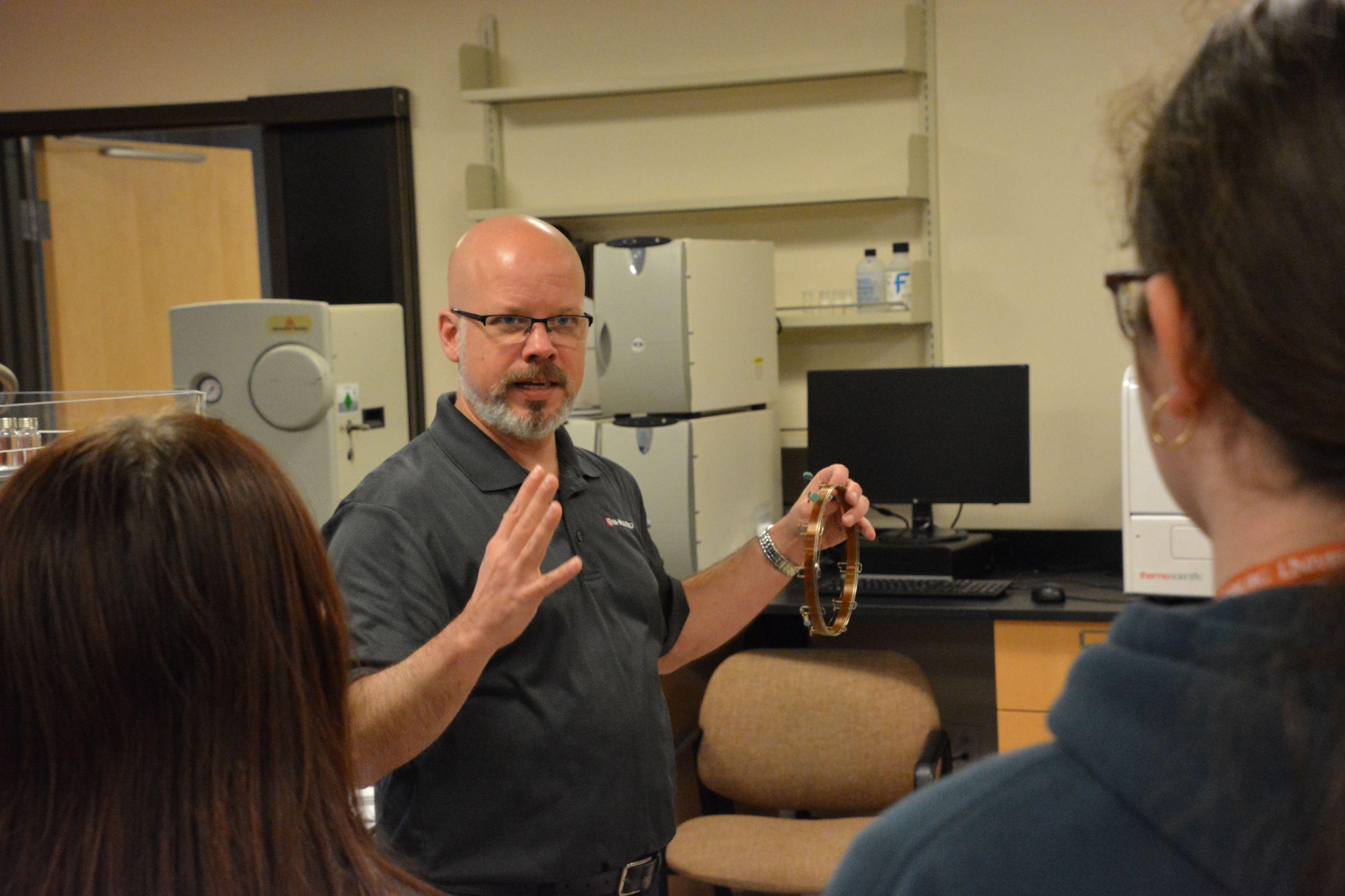 Representative from Shimadzu explains chemistry equipment to students at event