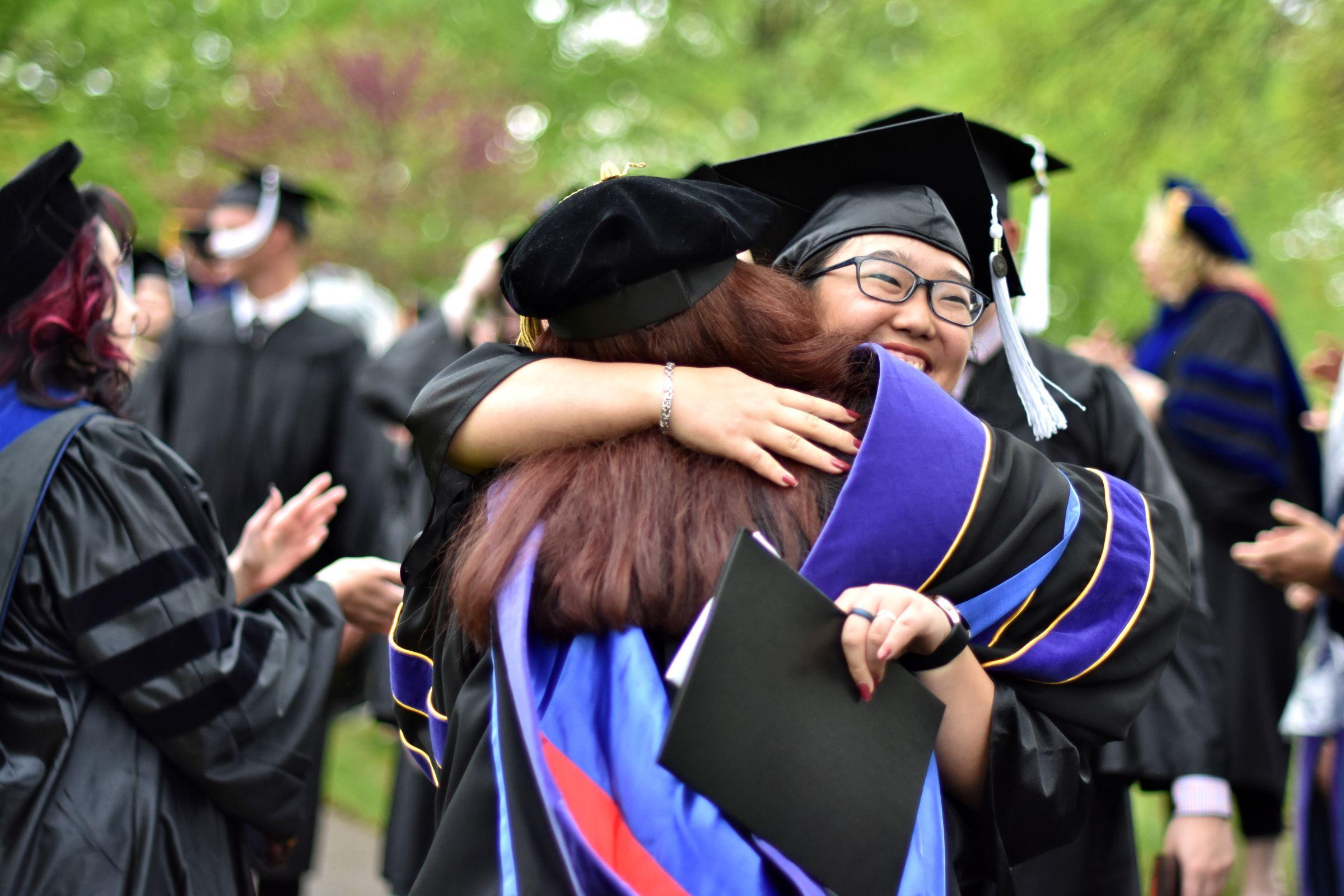 Student and faculty member embrace after the ceremony