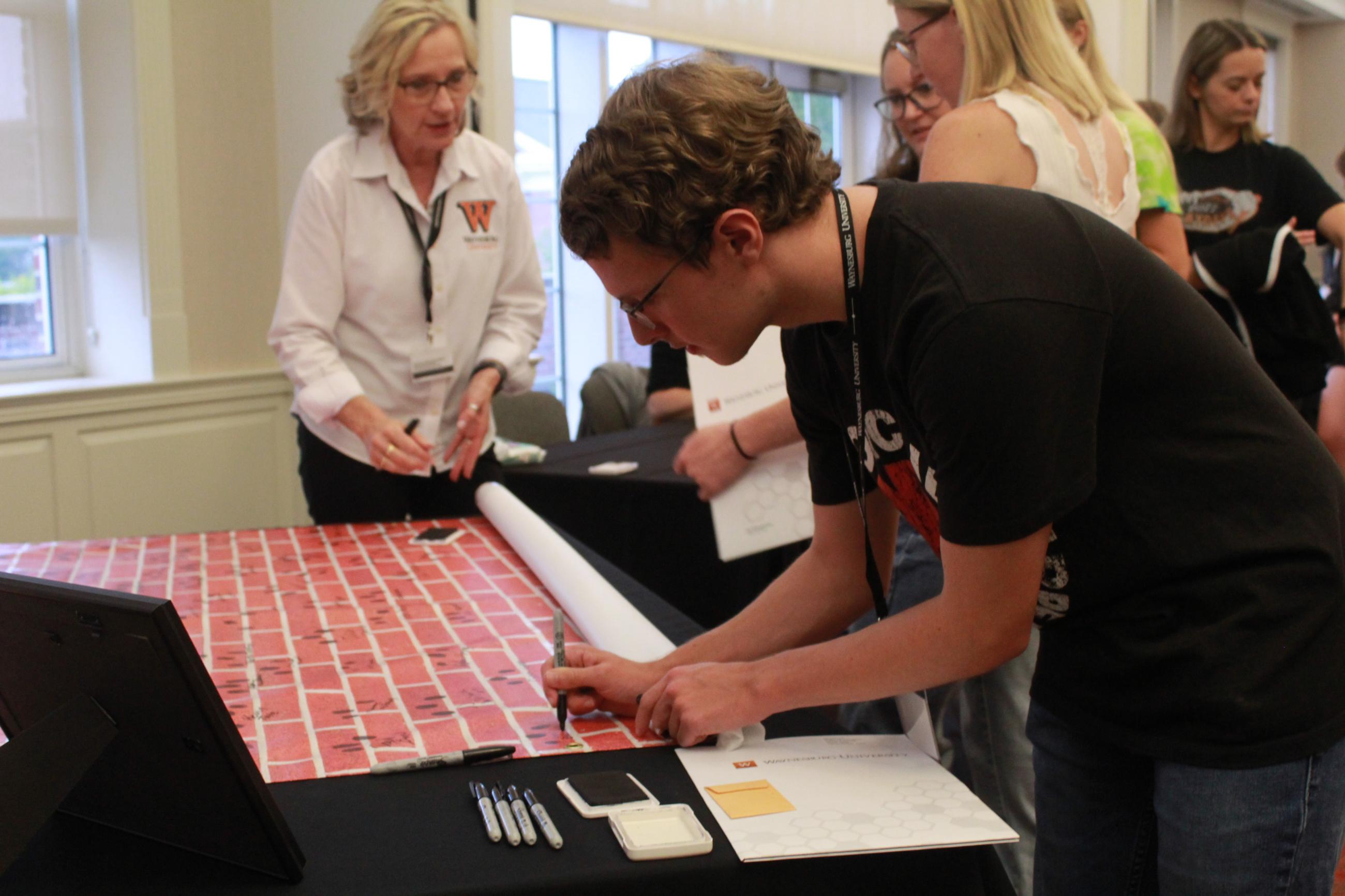 student putting fingerprints on banner