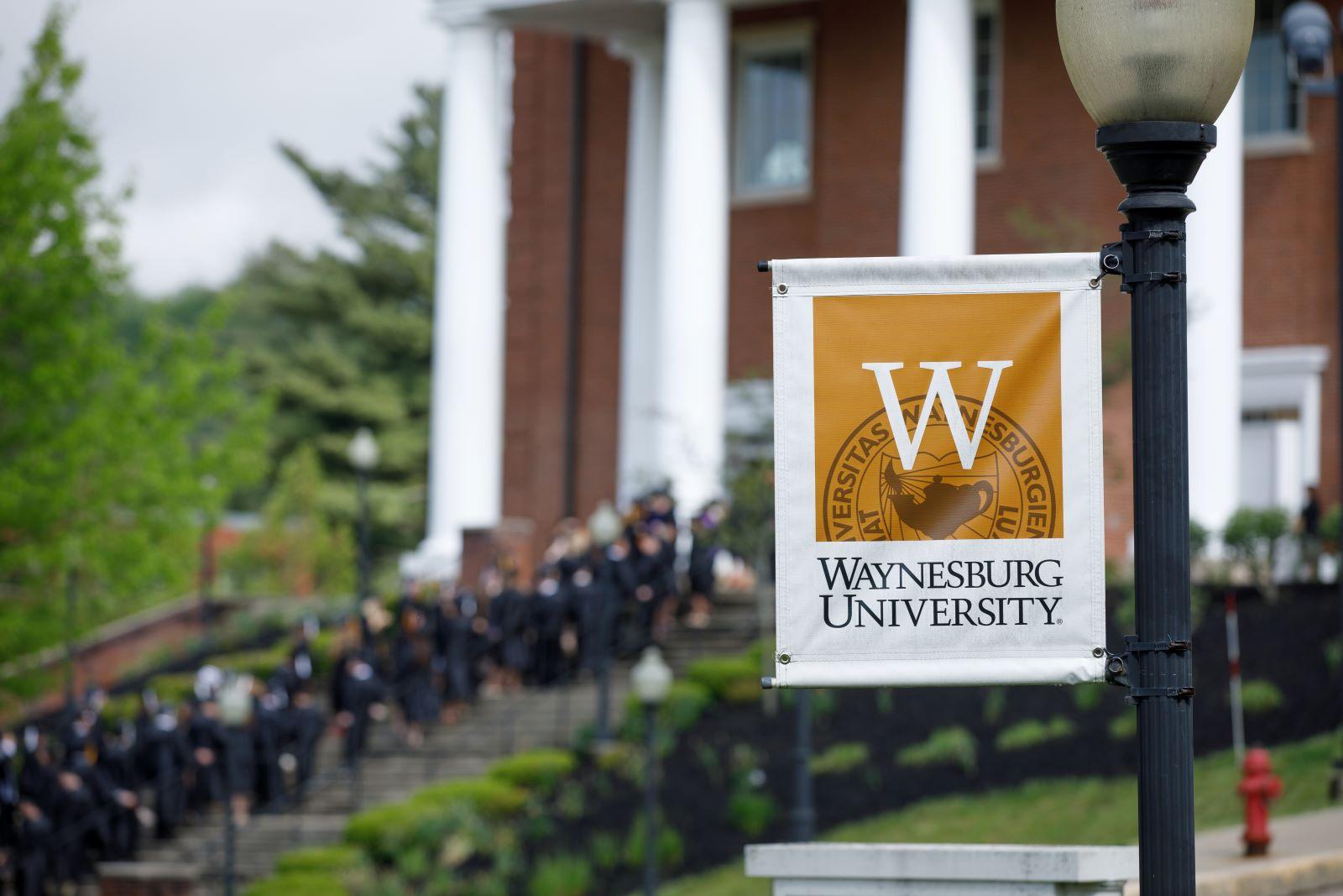 Waynesburg U sign with graduates in background