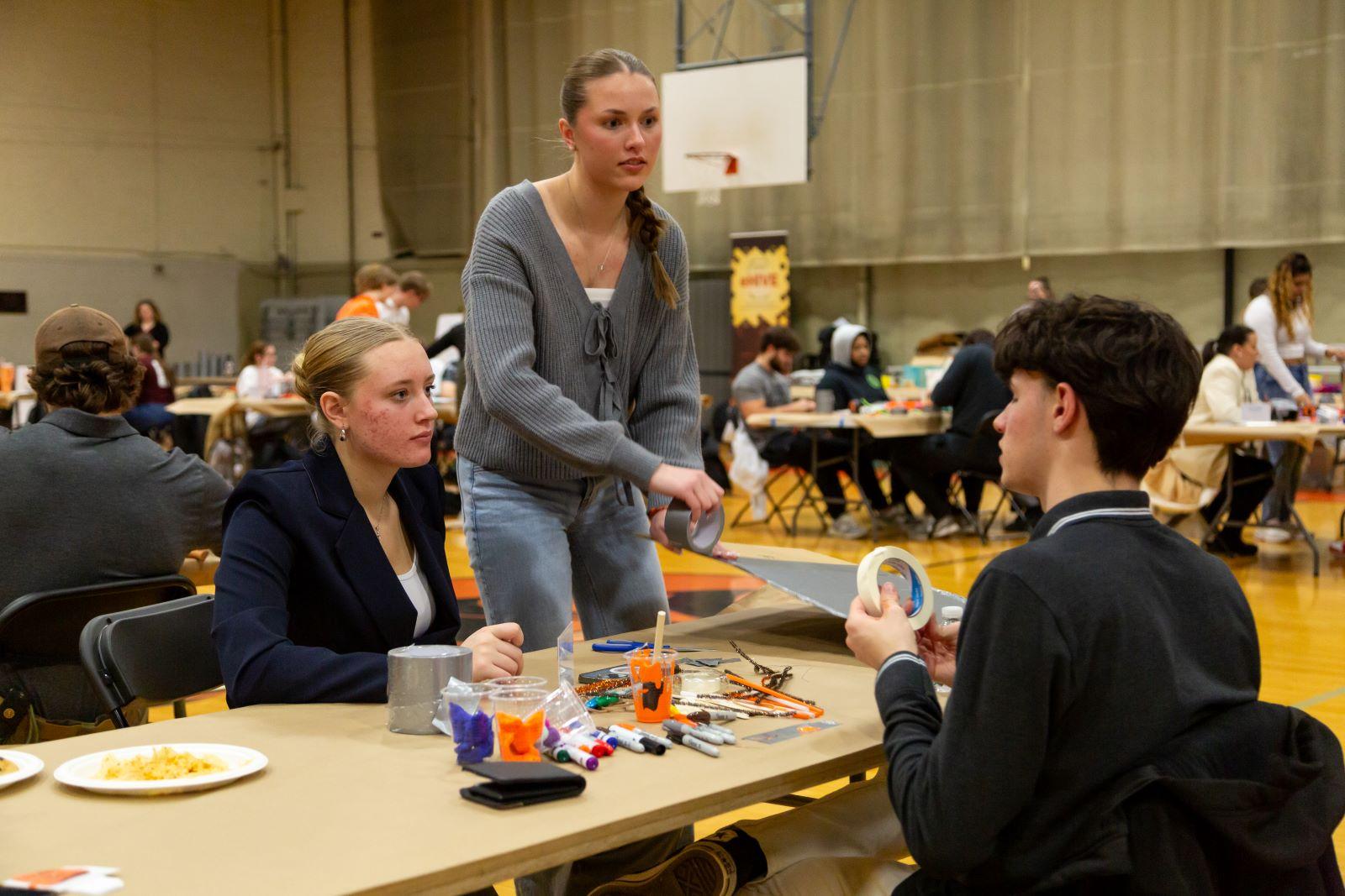 Three students collaborate and discuss at the table