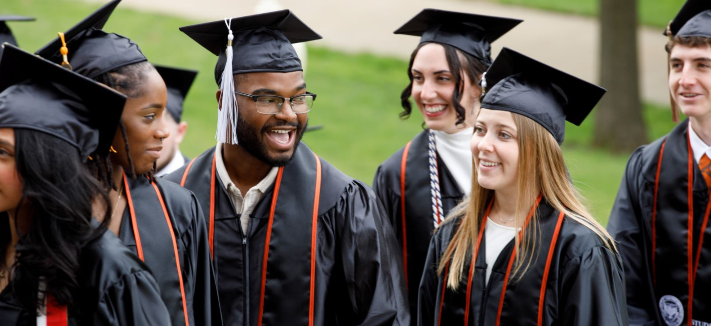 Waynesburg University 2025 graduates talking in cap and gown