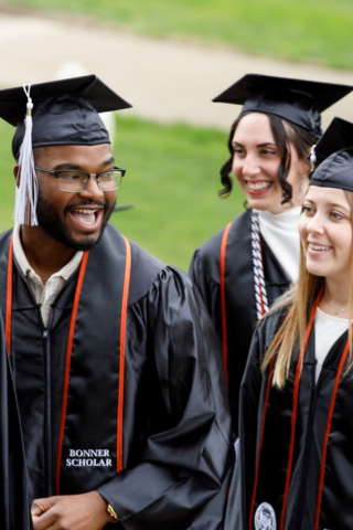 Waynesburg University 2025 graduates talking in cap and gown