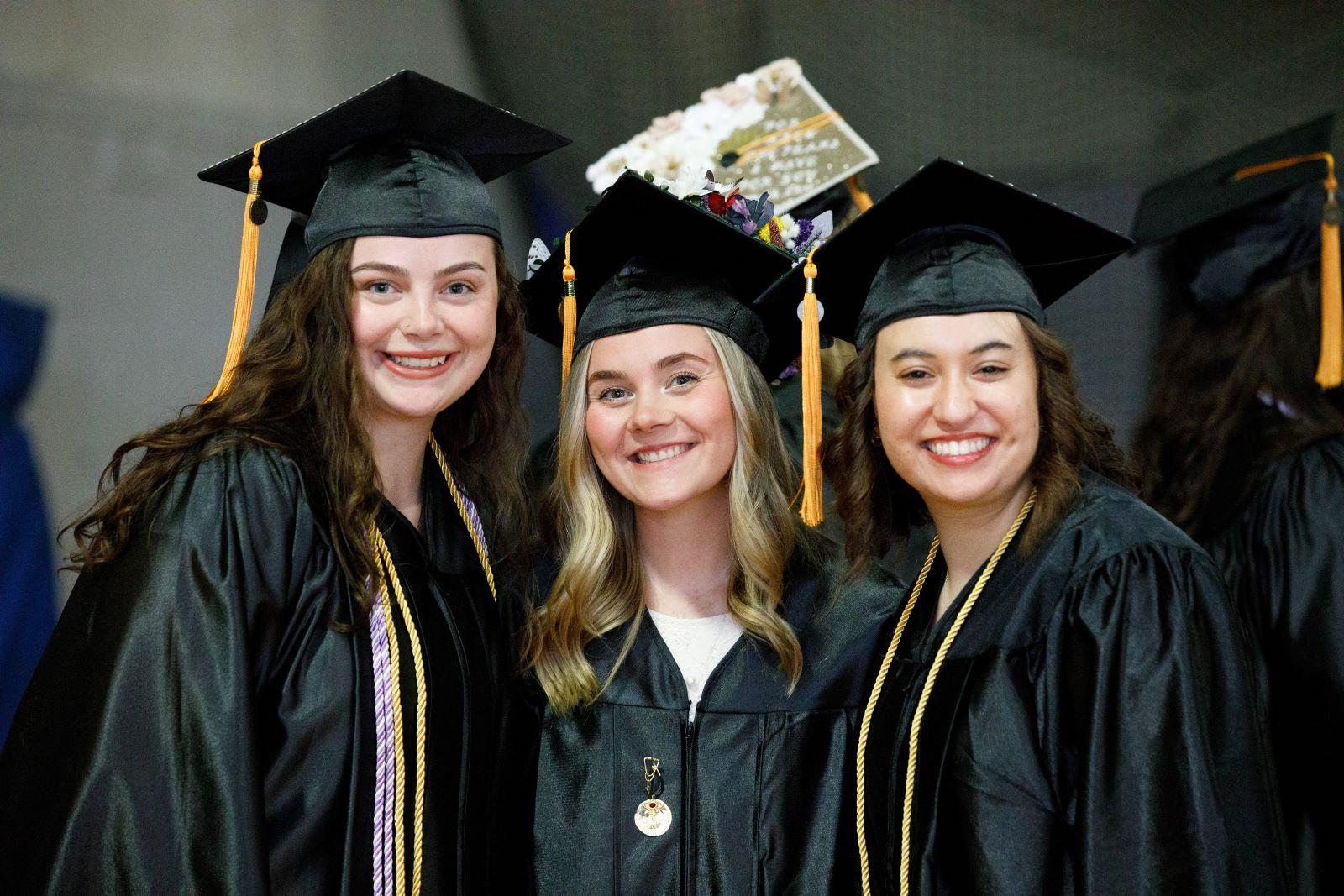 Three female graduates pose for a photo