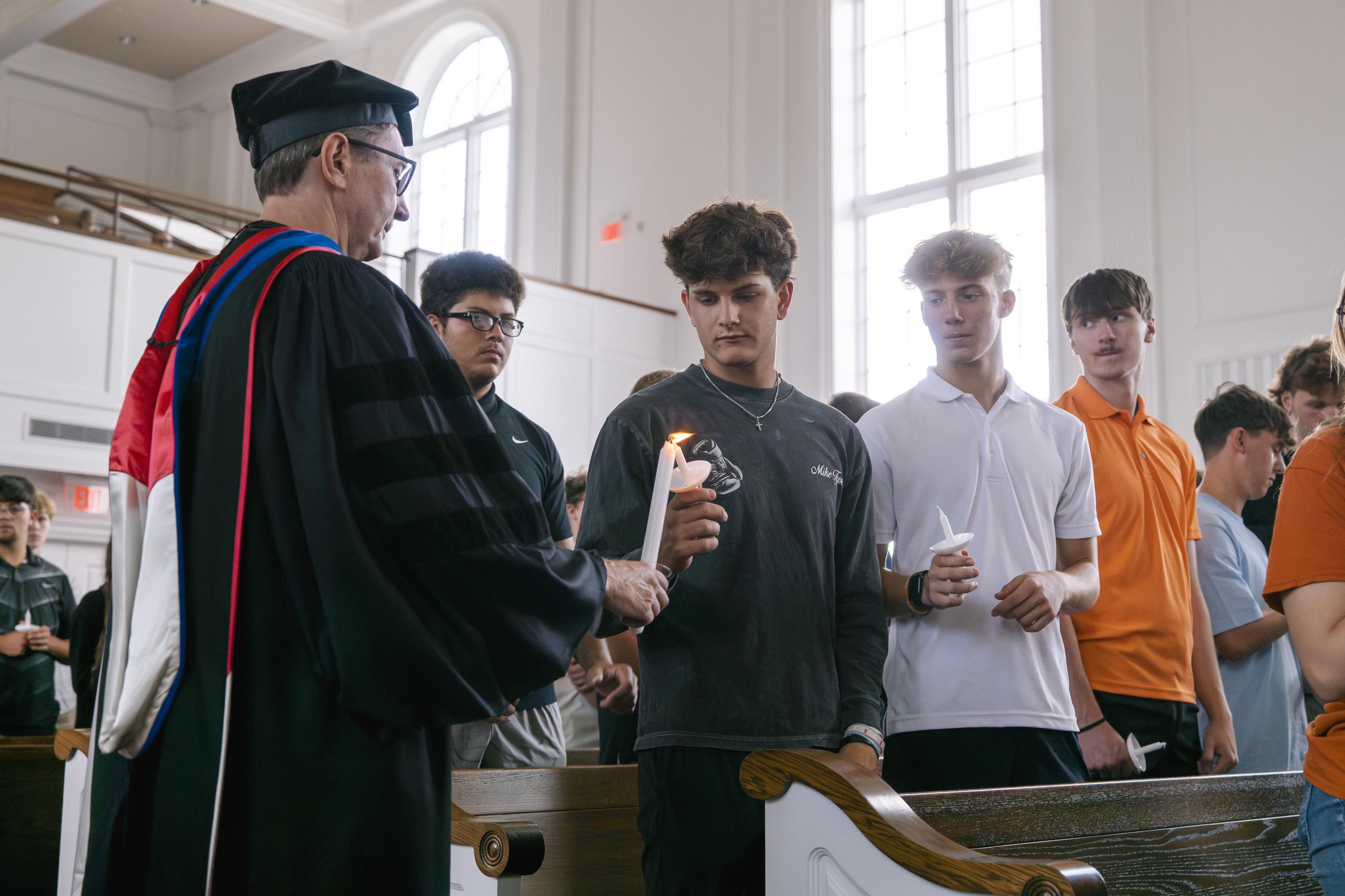 Faculty lighting students' candles