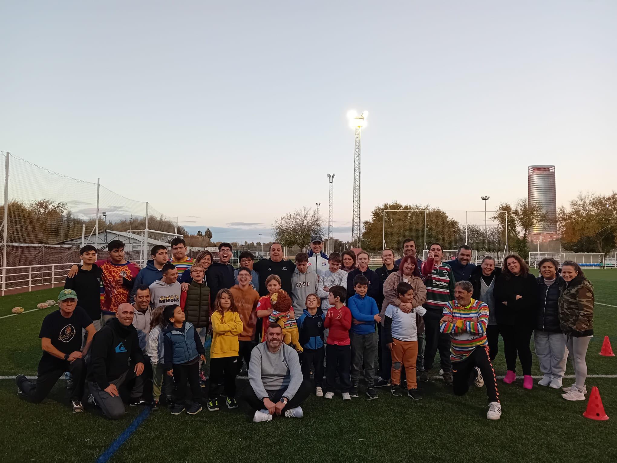 A group of young kids and adults gather for a picture on a soccer field. 