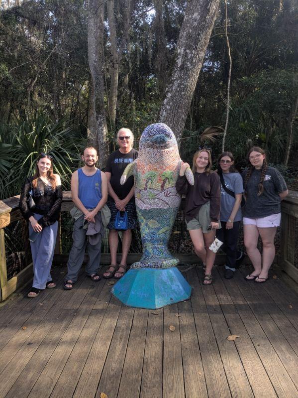 Waynesburg students and faculty leaders stand next to acolorful, upright manate statue