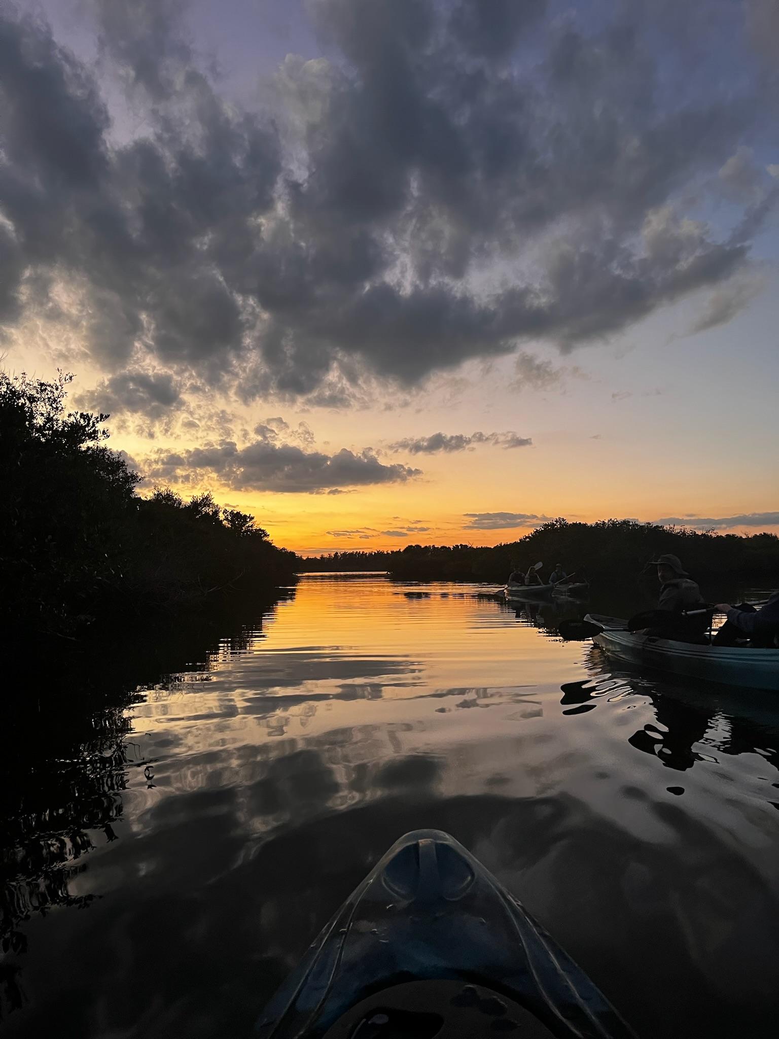 The sun sets in the distance. The picture was taken from inside a kayak.