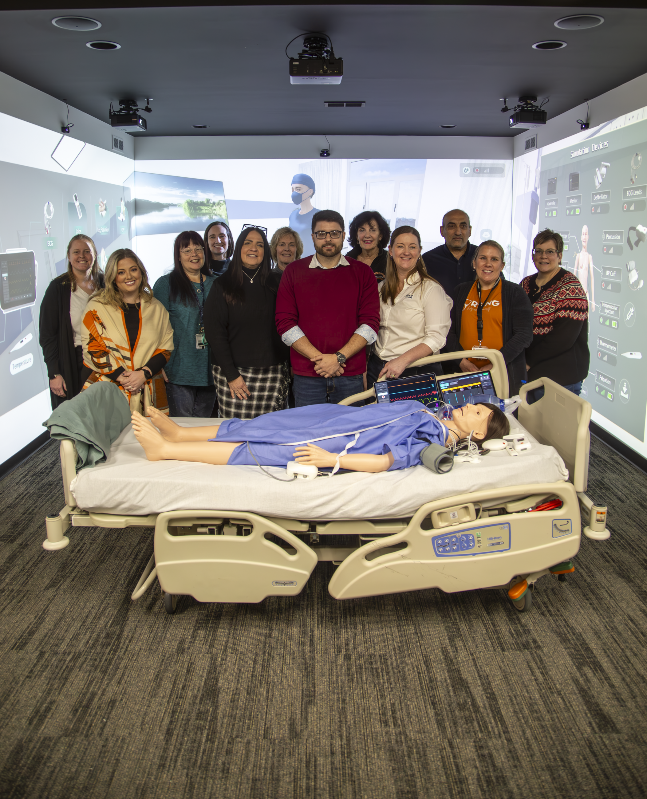 Group of nursing faculty and Nasco representatives pose in the Nursing Immersion Room .