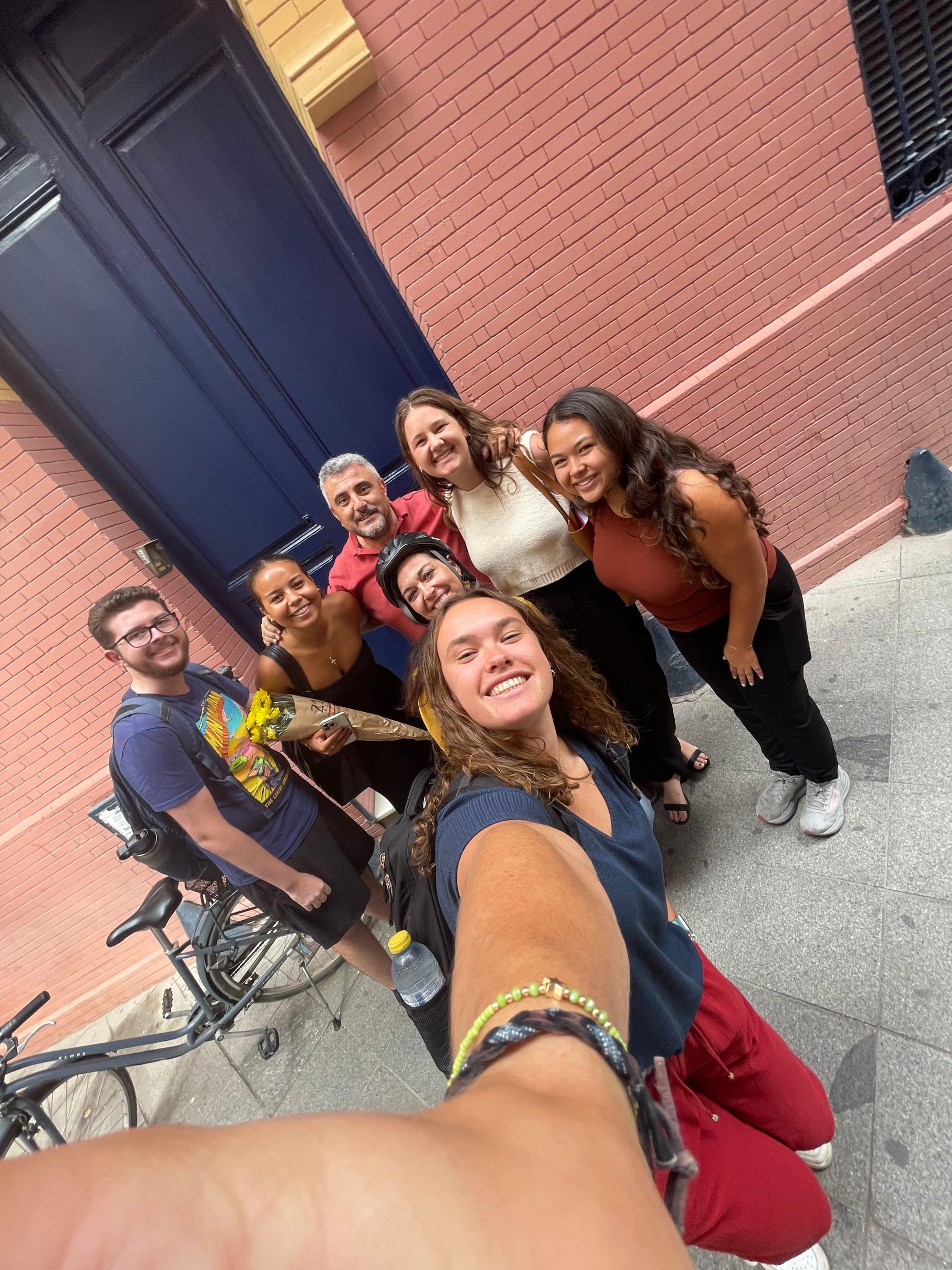 Natalie takes a photo of herself, classmates and teachers outside a brick building. 