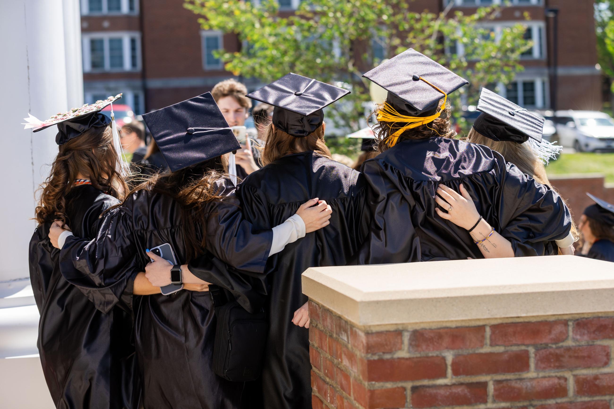 Group of graduates with their arms around each other. 