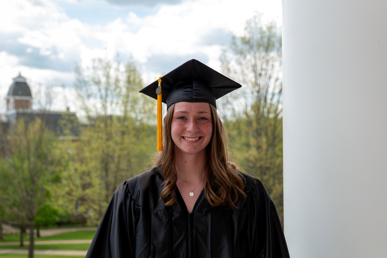 Alison Landon poses in her cap and gown on campus.