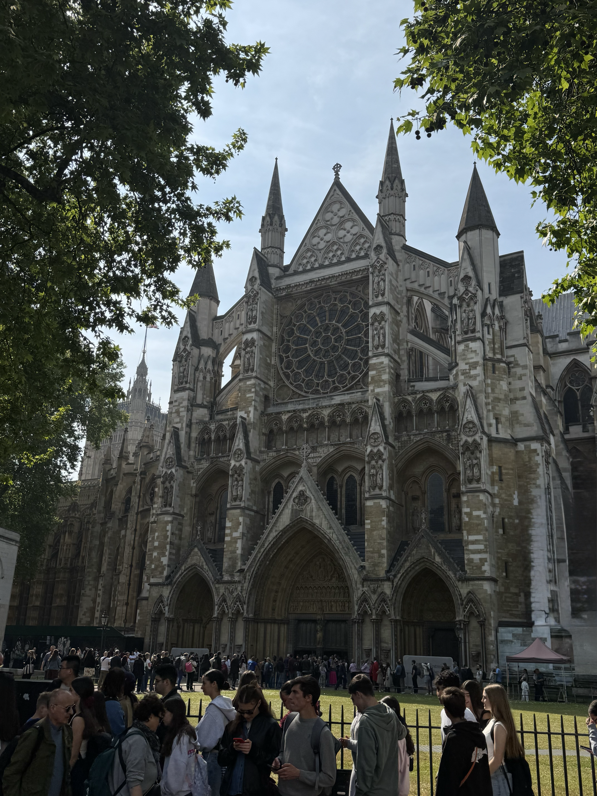 A large gothic style cathedral with trees and people walking in the foreground