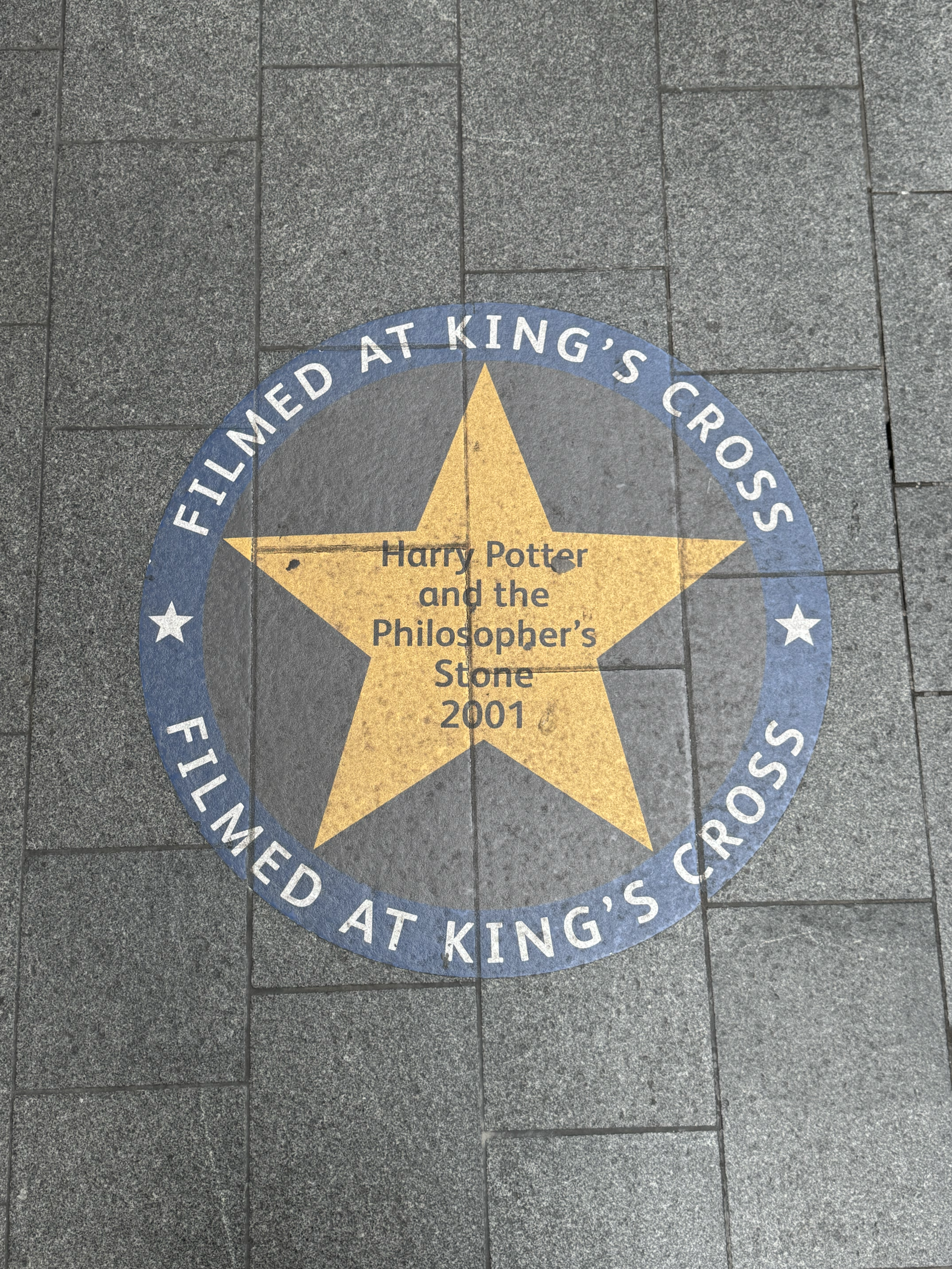 A star emblem on the stone floor which reads "Filmed at King's Cross, Harry Potter and the Philosopher's Stone