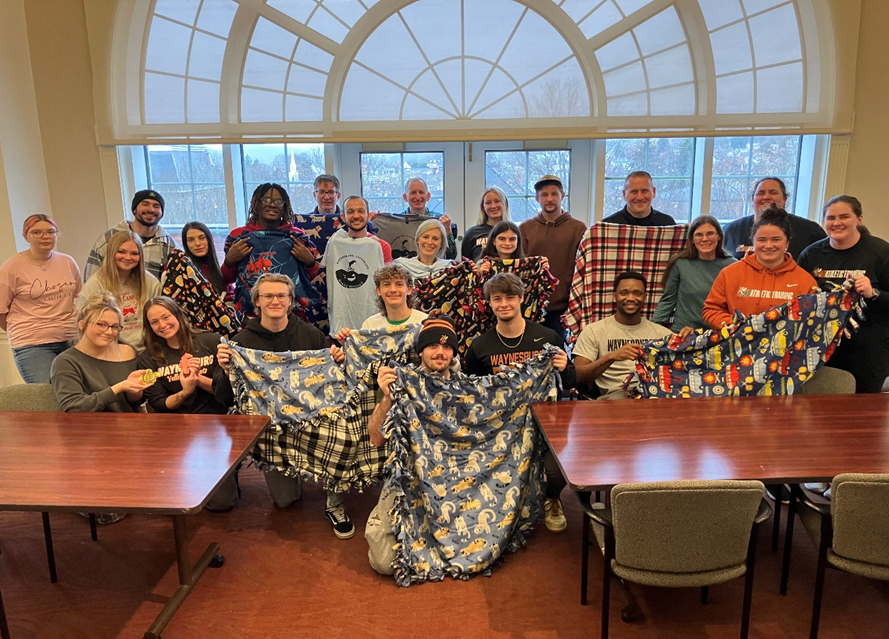 A group photo of students with the handmade blankets.