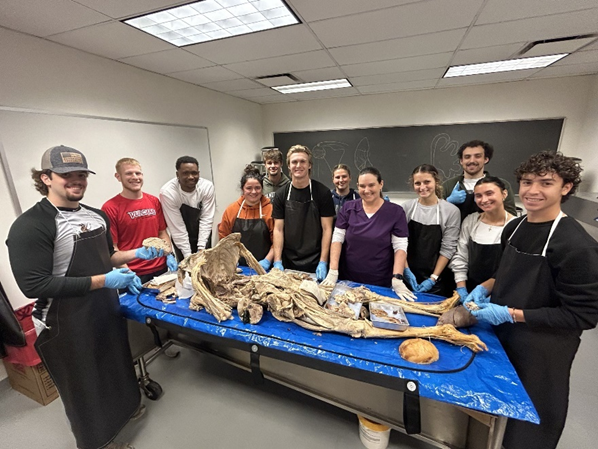 A group photo of the full class in the cadaver anatomy lab.