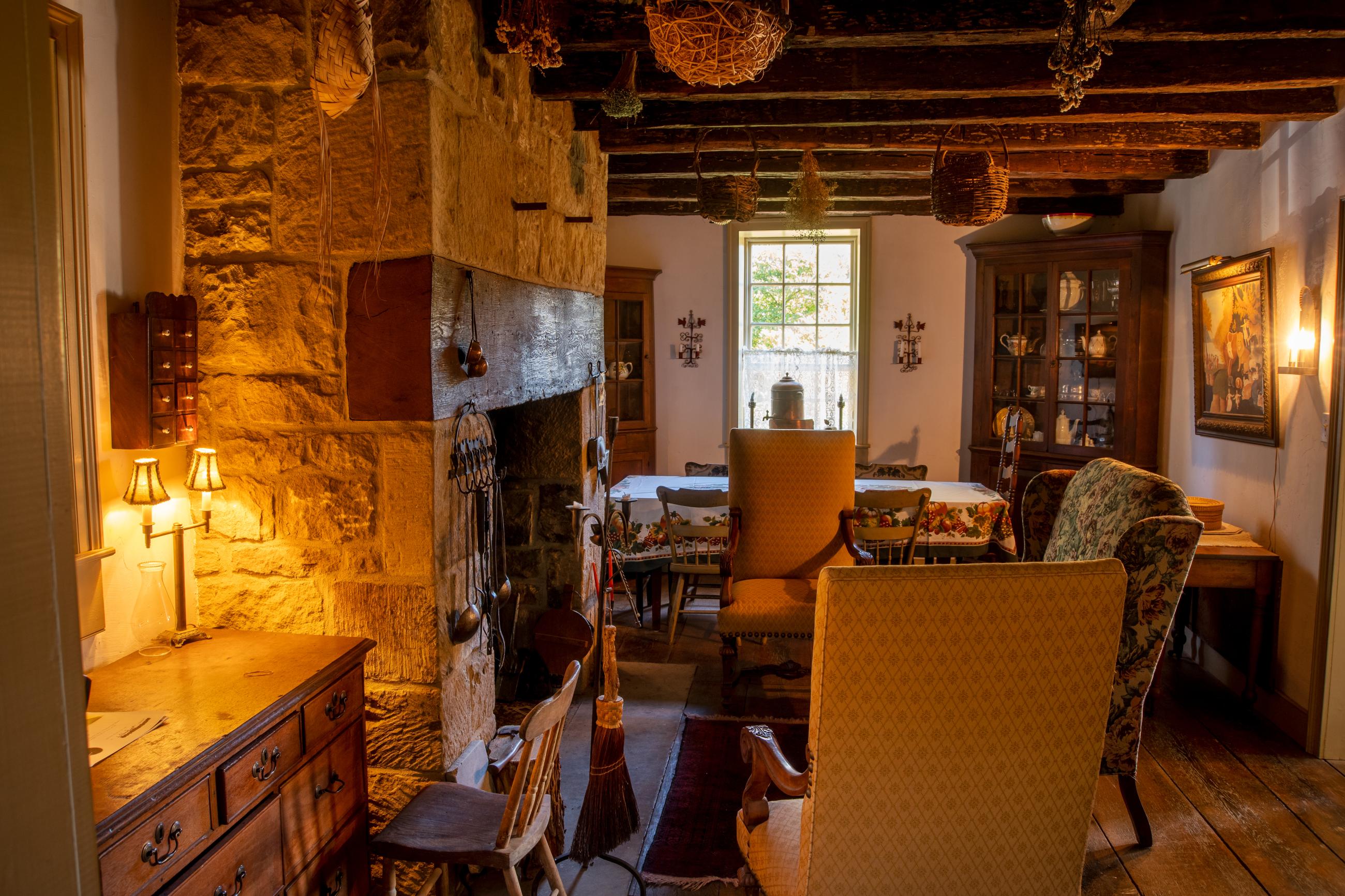 Chairs gathered together in front of a stone fireplace with a lamp casting a yellow glow.