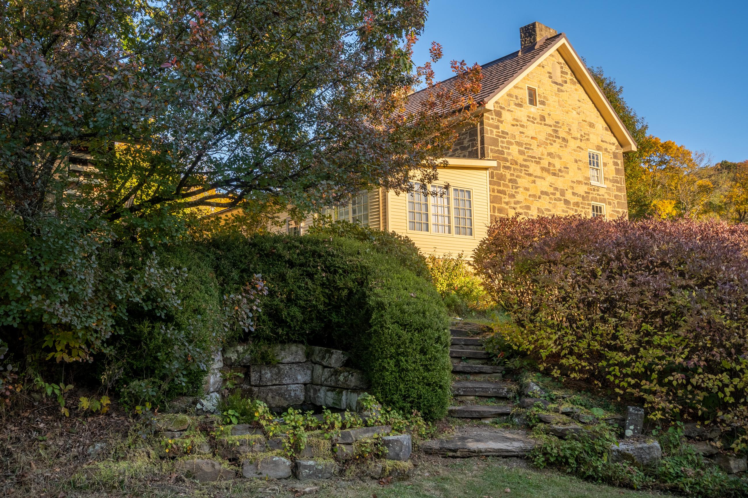 Side view of the historic house at the Ecology Center with stone steps leading up to it.