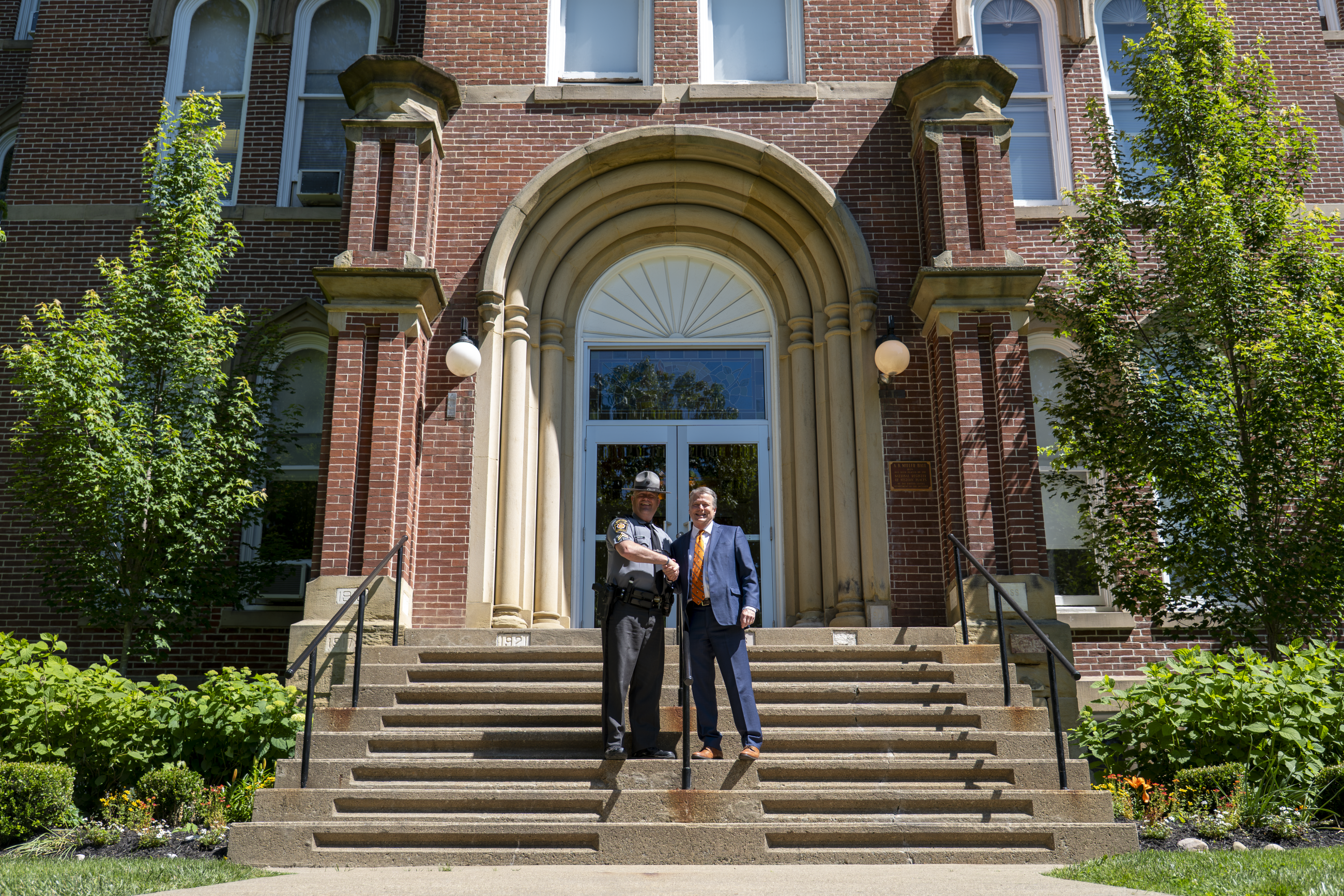 President Lee and CPL. Marc Ziegler - Western Unit Recruitment Supervisor, standing on the front steps of Miller Hall.