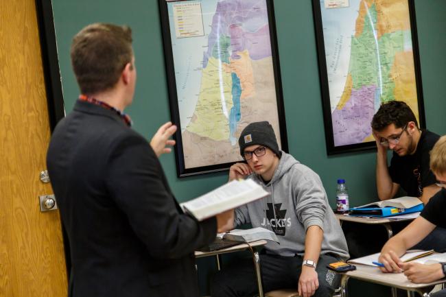 classroom photo with instructor facing two students at desks
