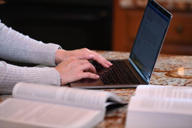 Hands typing on a laptop