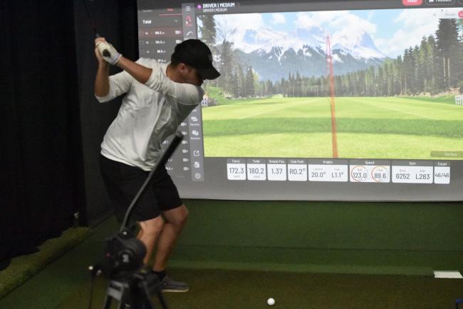 student swinging at golf simulator