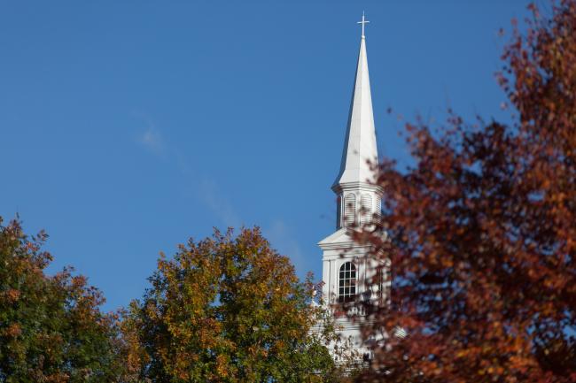 Image of Roberts Chapel behind trees with fall leaves