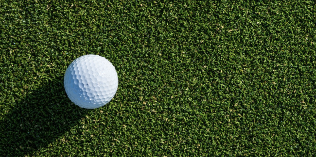 Golf ball with shadow on a putting green