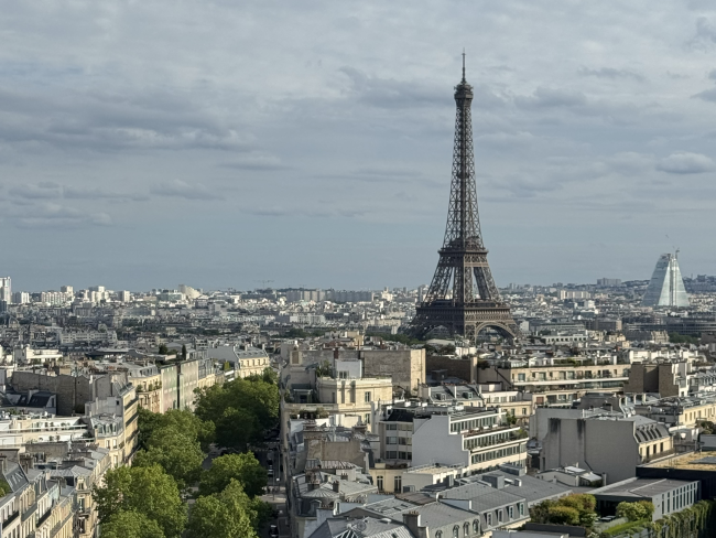 The Eiffel Tower, a tall metal industrial structure, towers above the streets of Paris.