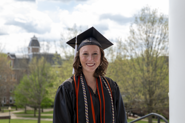 Riley Ruffley pictured in her cap and gown with Miller Hall in the background
