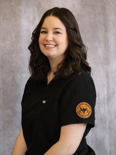 A female nursing student in scrubs poses for a professional headshot