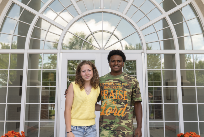 Natasha and Tyler standing in front of arched windows.