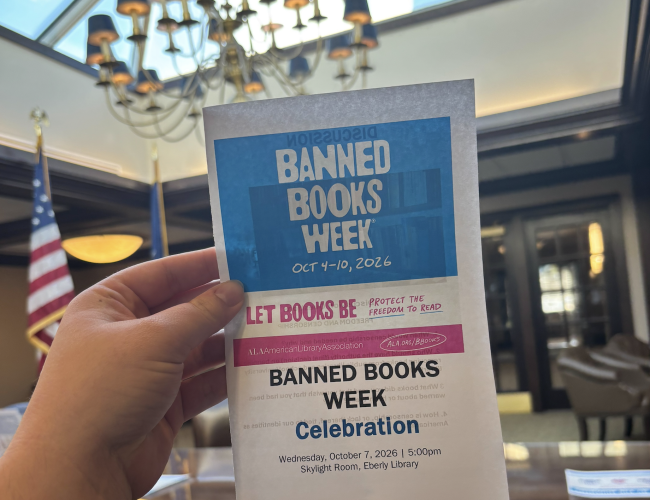 A hand holding a Banned Books Week celebration flyer in the Skylight Room in Eberly Library
